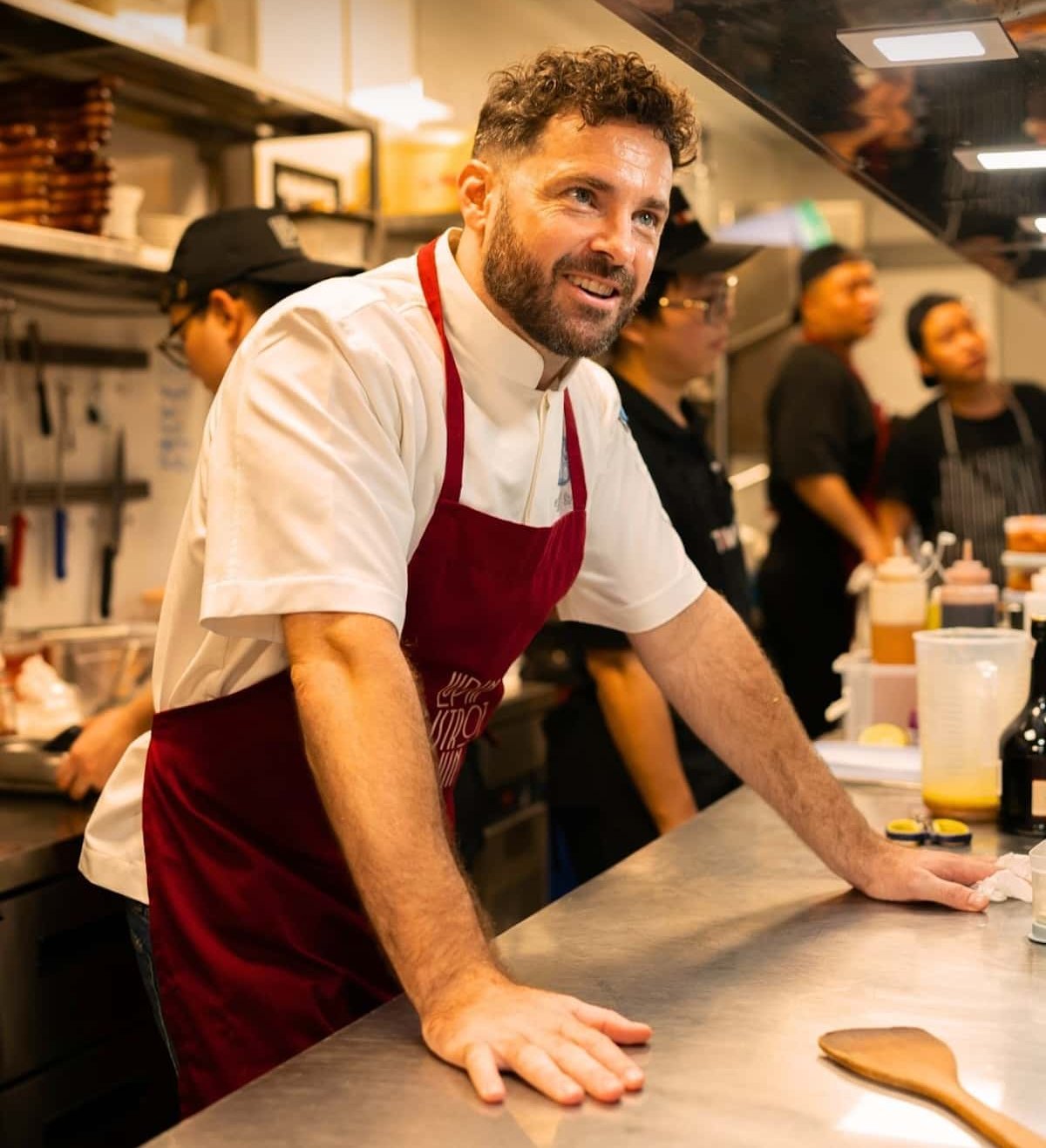 A chef with his hands on the table in a kitchen.