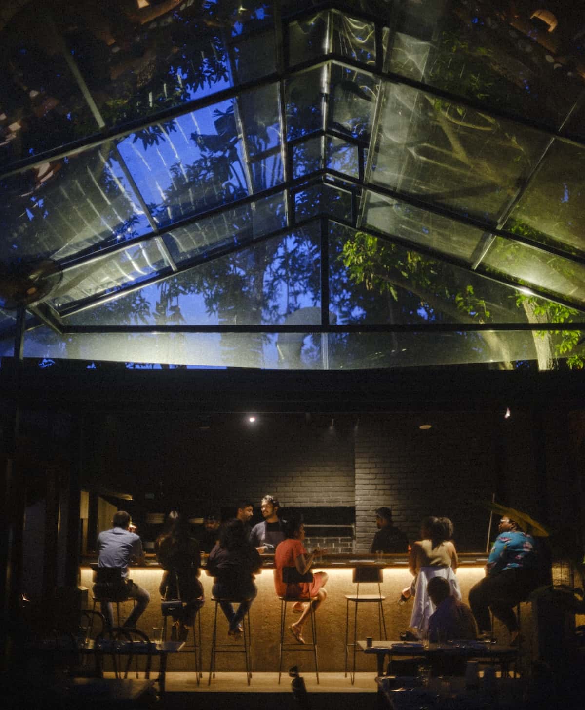 A dark room with people sitting at the counter.
