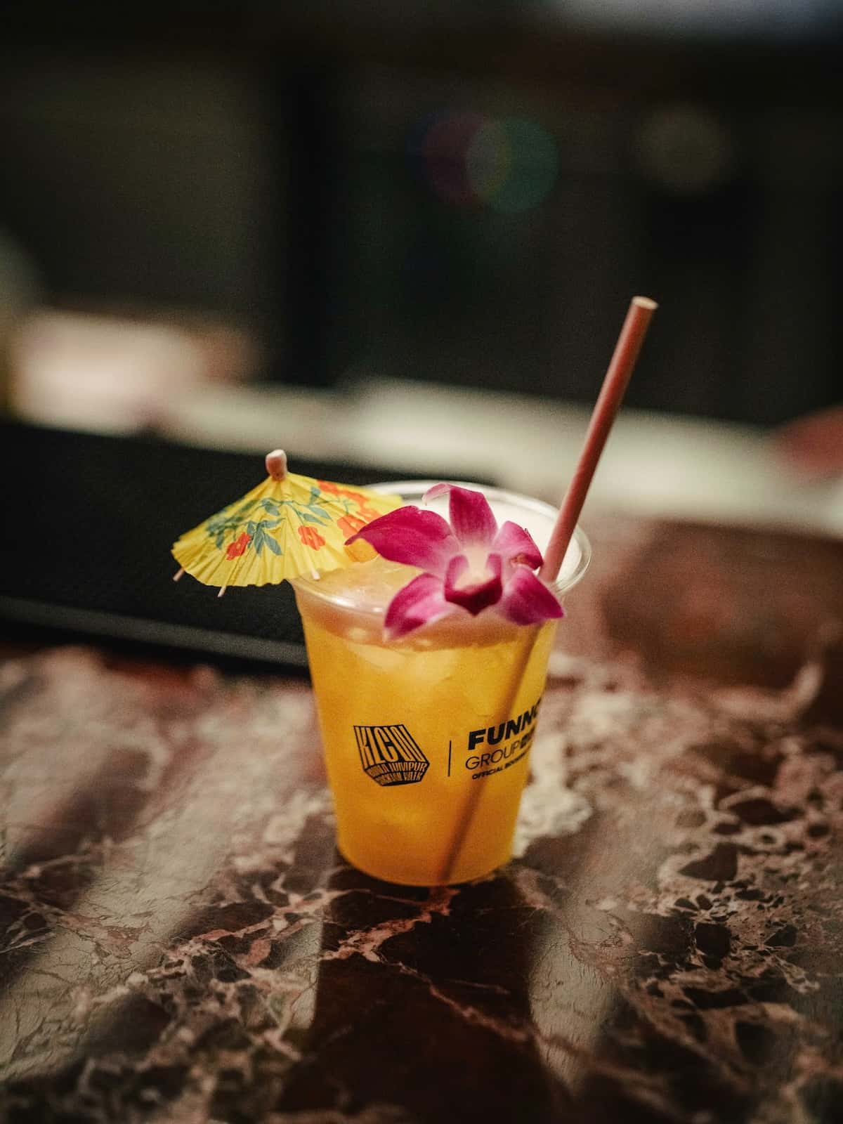 A cocktail with an umbrella and flower on top.