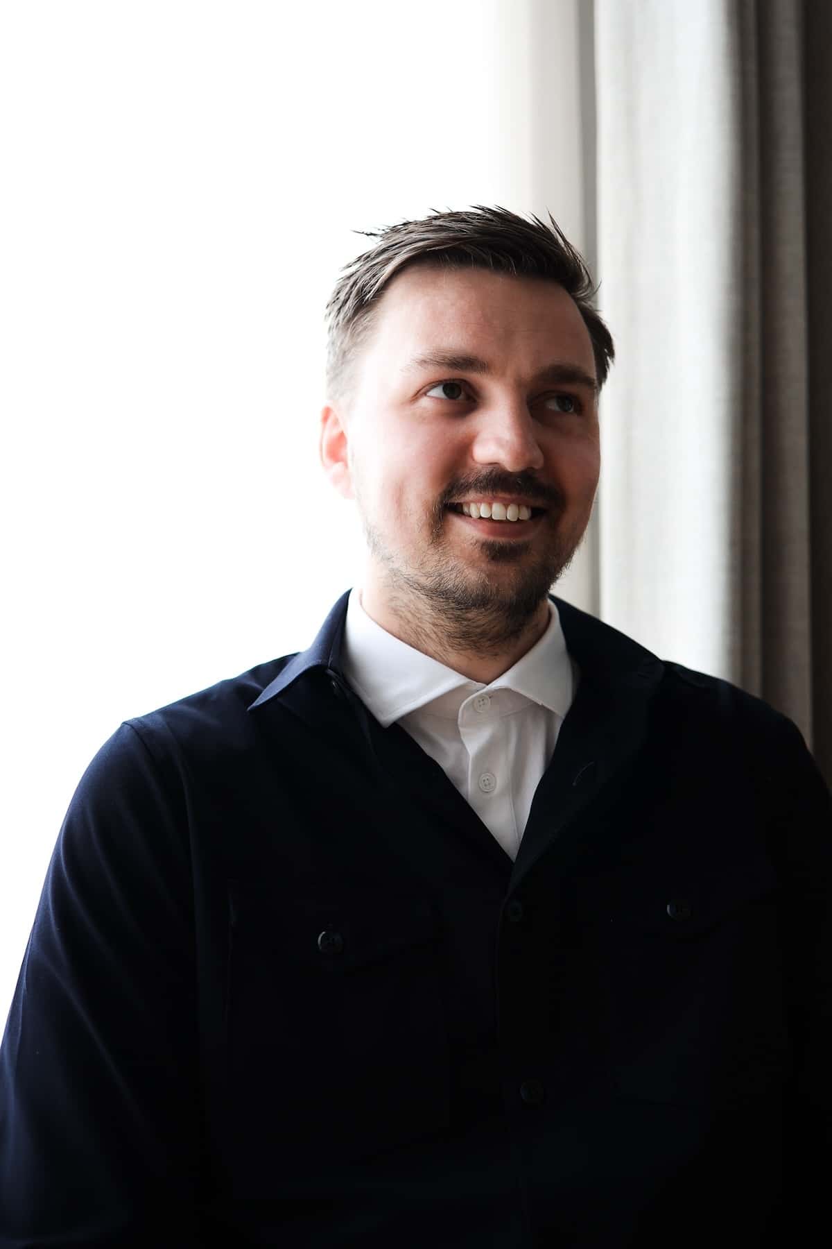 A man by a window smiling. 