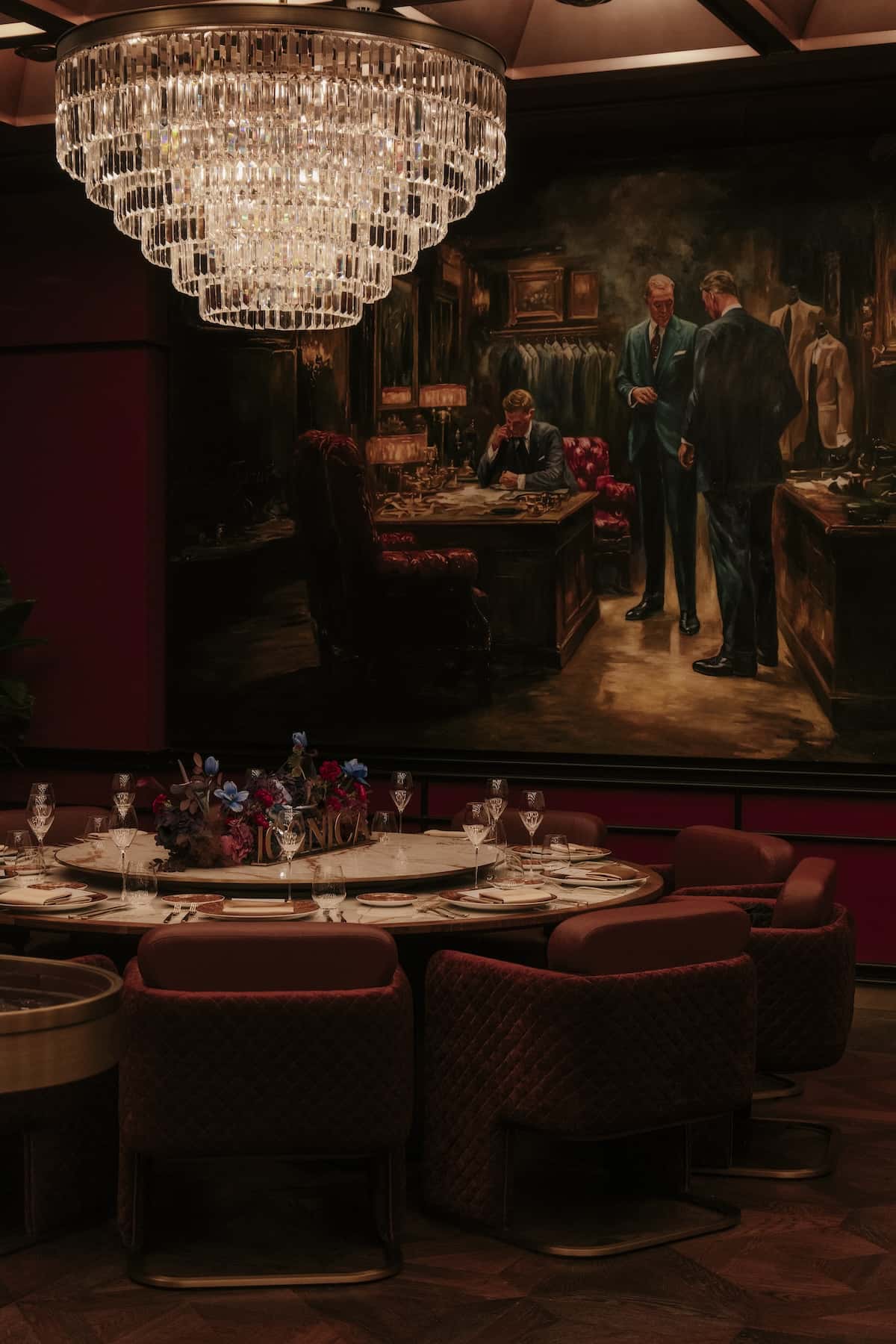 a chandelier over a table with a painting on the wall