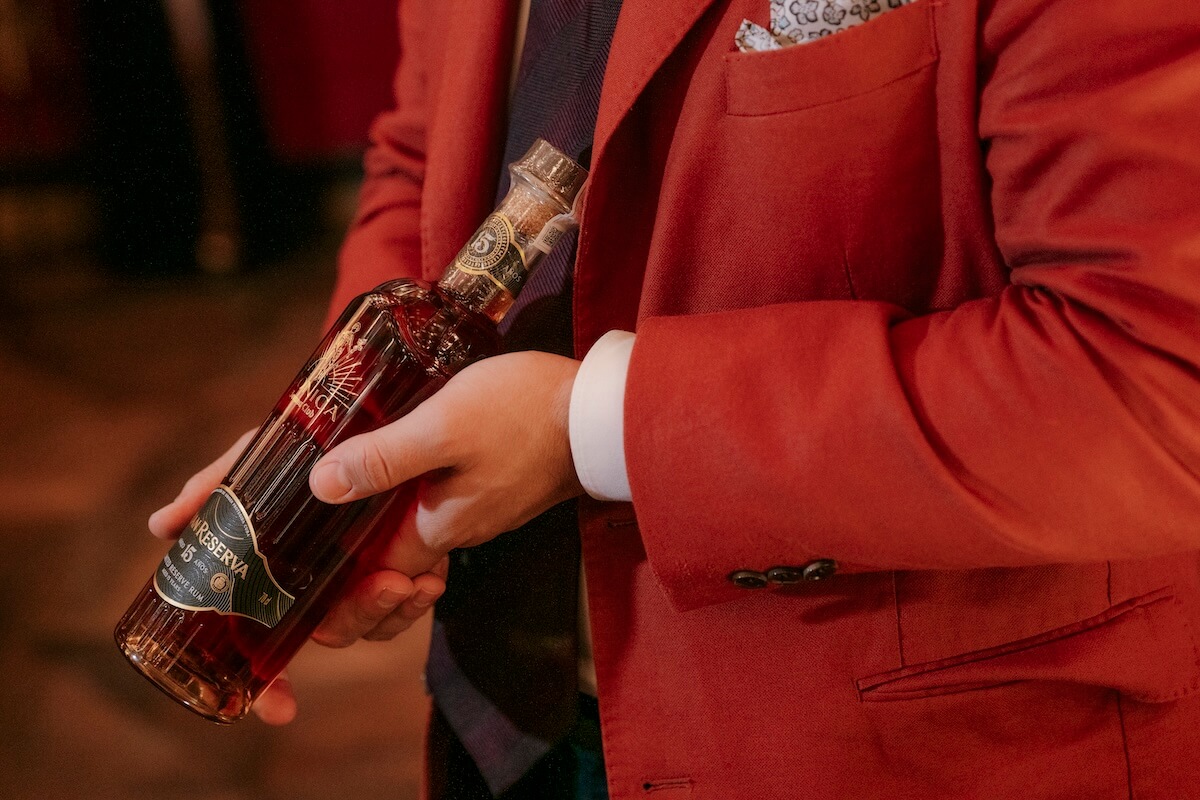 A man in a red jacket holding a bottle.