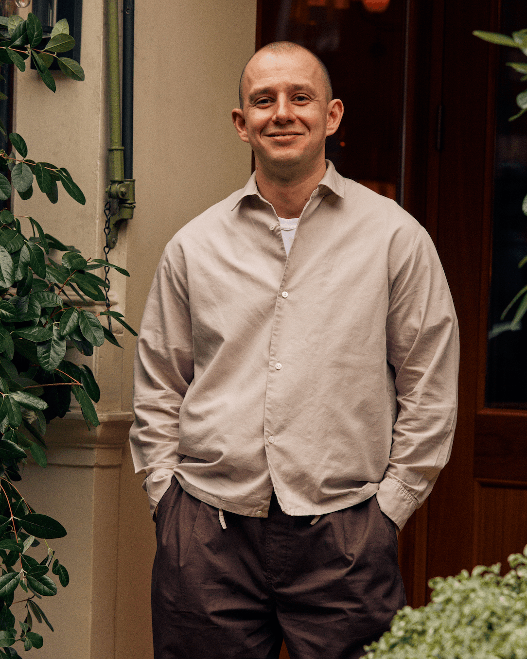 A man in a beige shirt smiling.