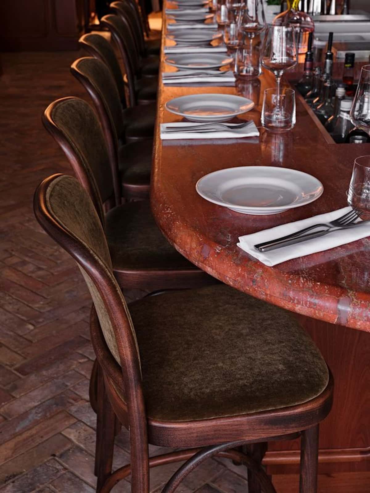 A curved counter with chairs and plates.