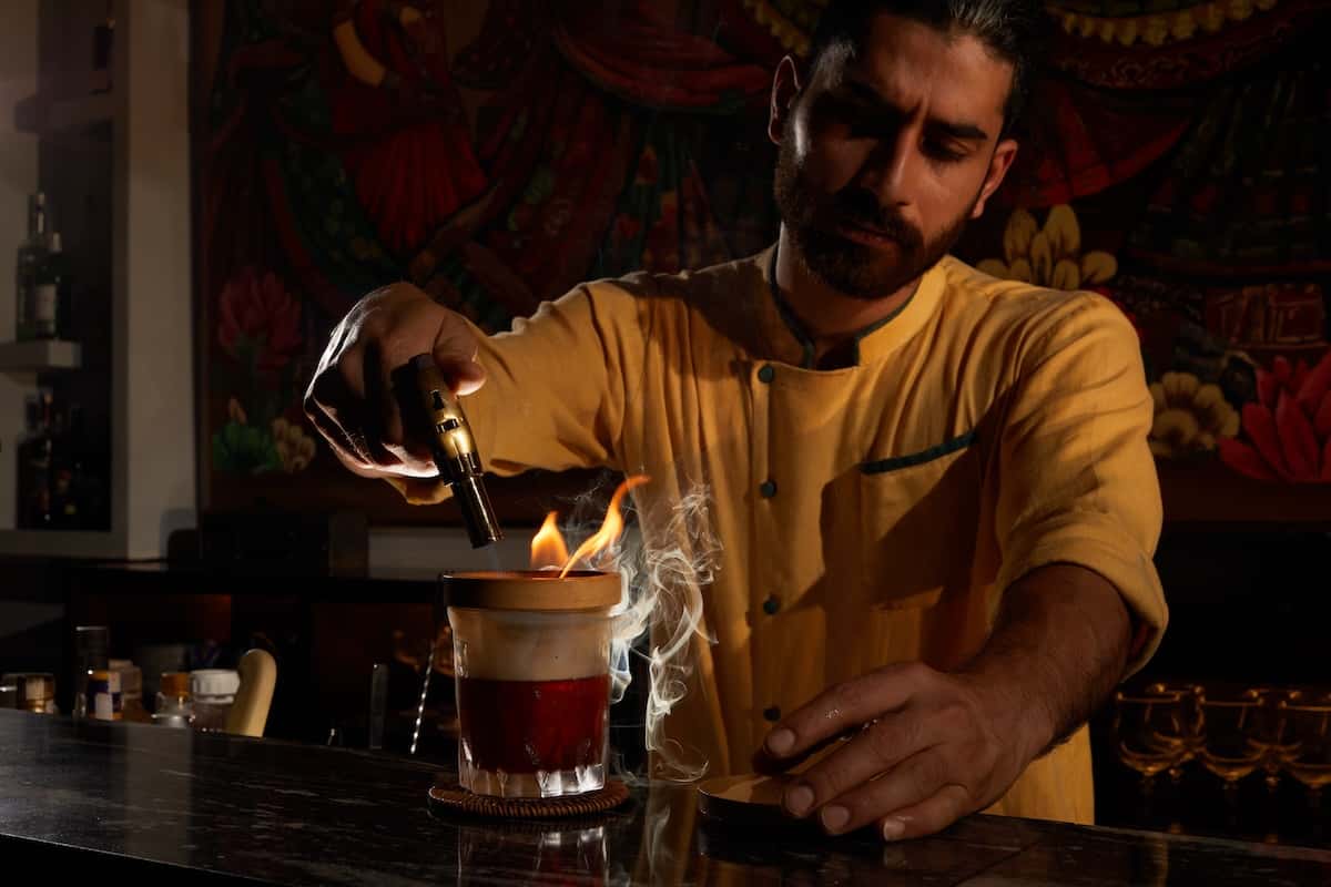 A bartender making a cocktail with fire and smoke.